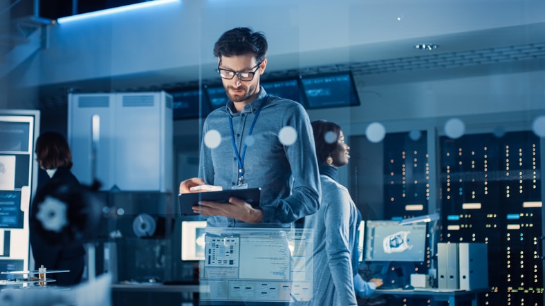 A man using a tablet in an IT control room